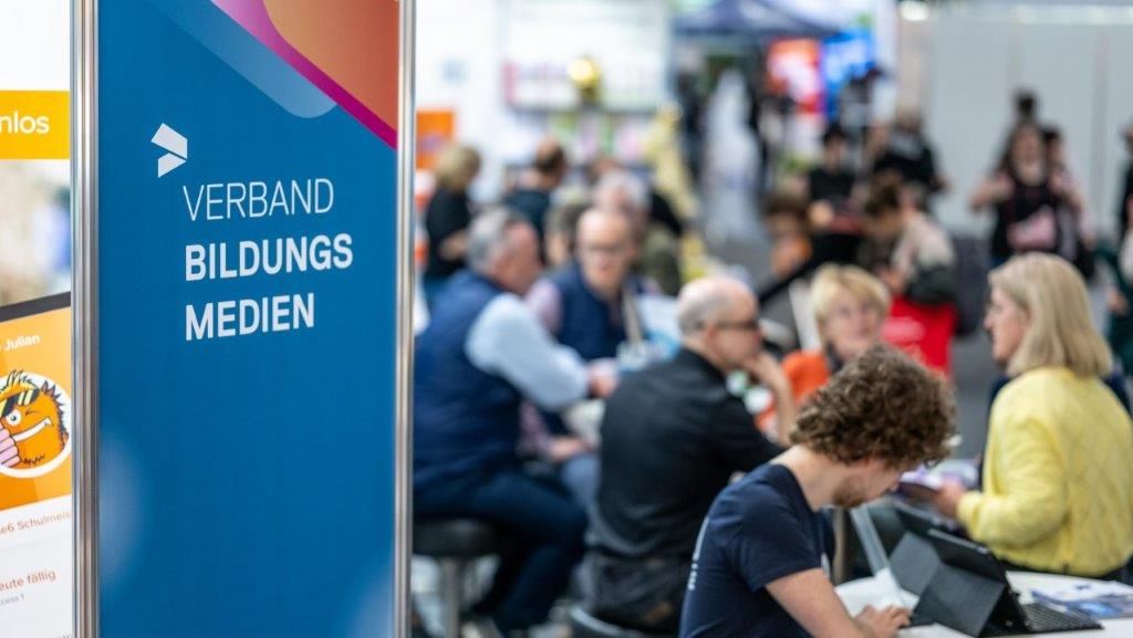 Messebesucher/-innen sitzen am Stand des Verband Bildungsmedien