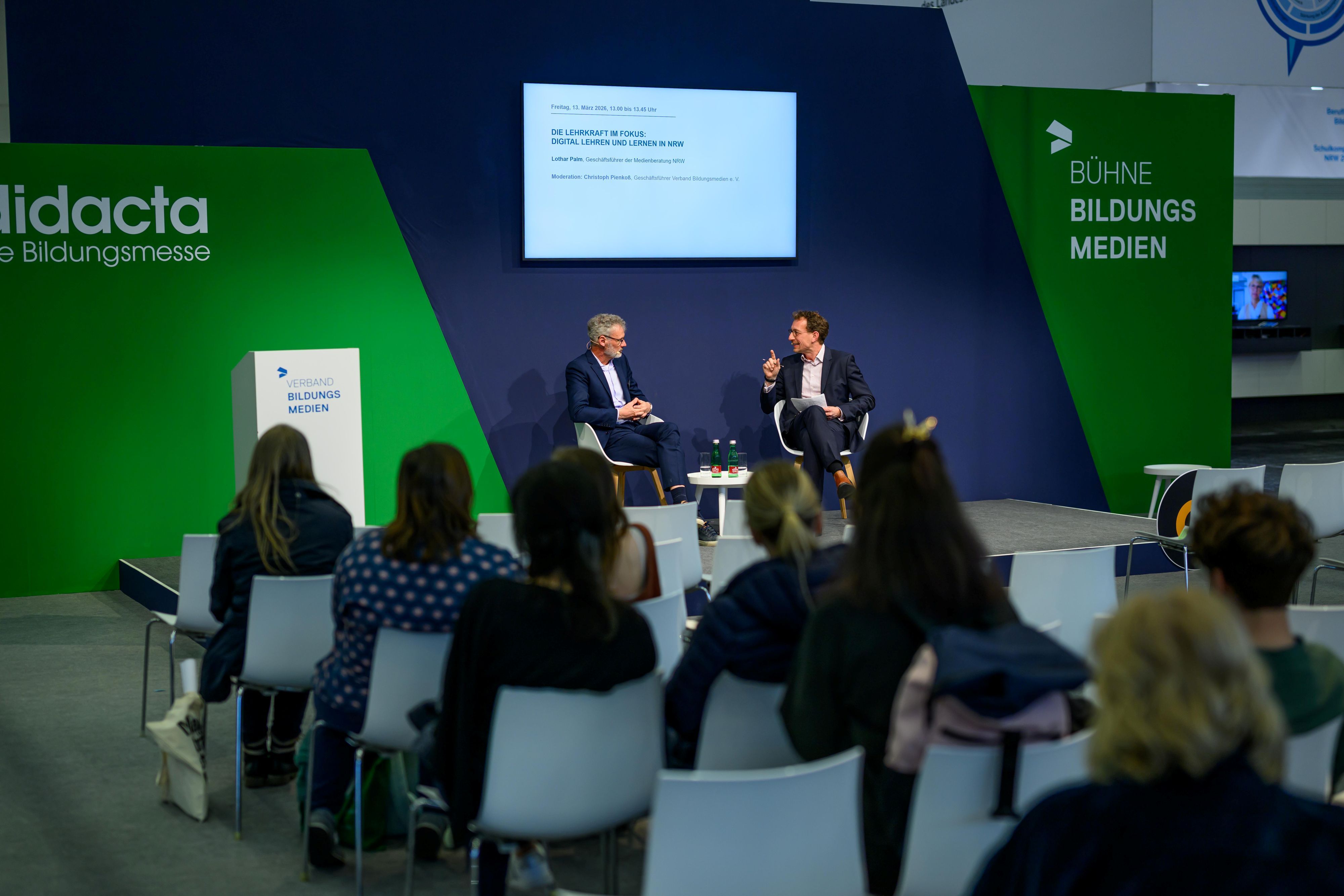 Christoph Pienkoß unterhält sich vor Publikum auf der Bühne mit Lothar Palm