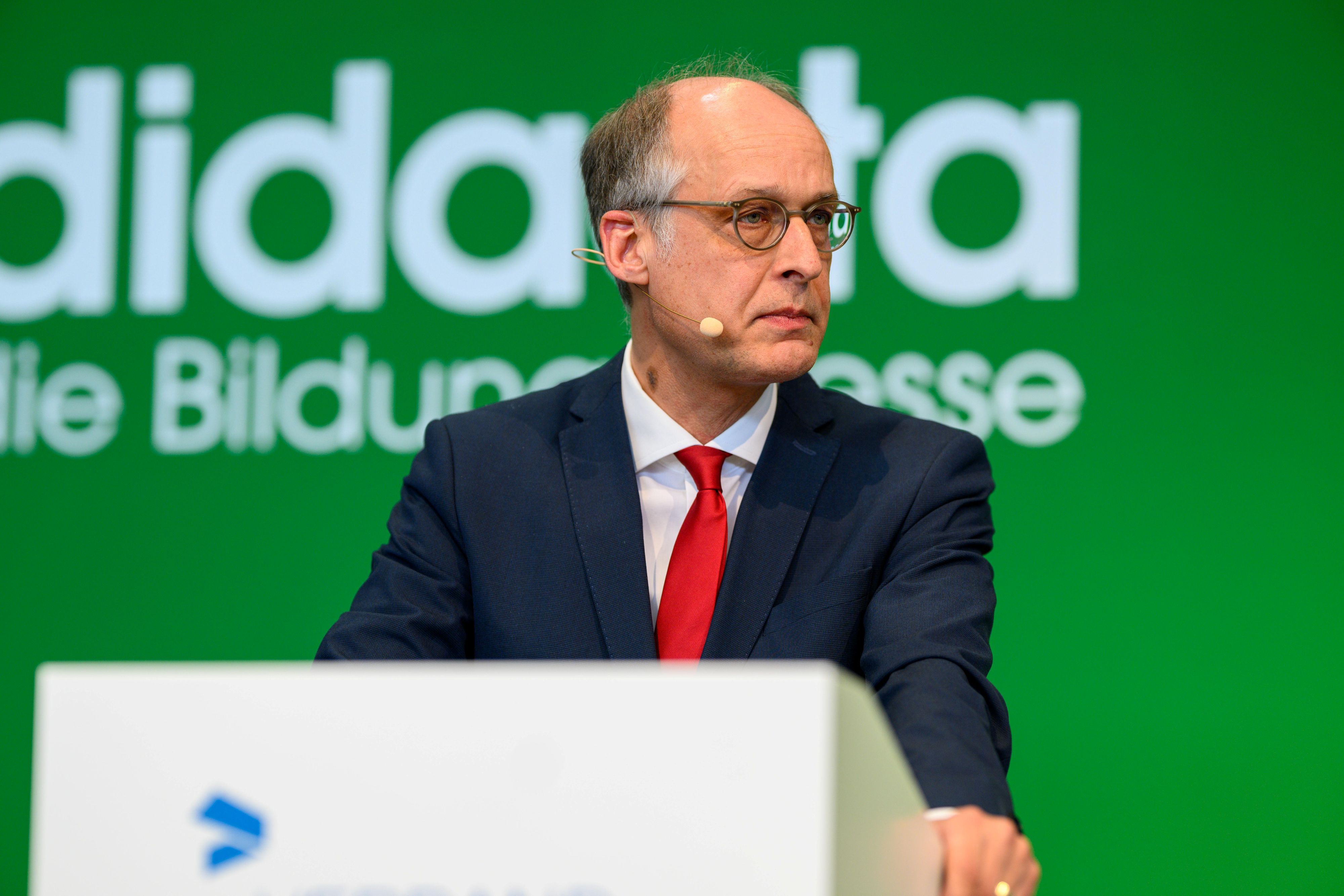 Staaatssekretär Dr. Mauer steht am Pult und schaut ins Publikum
