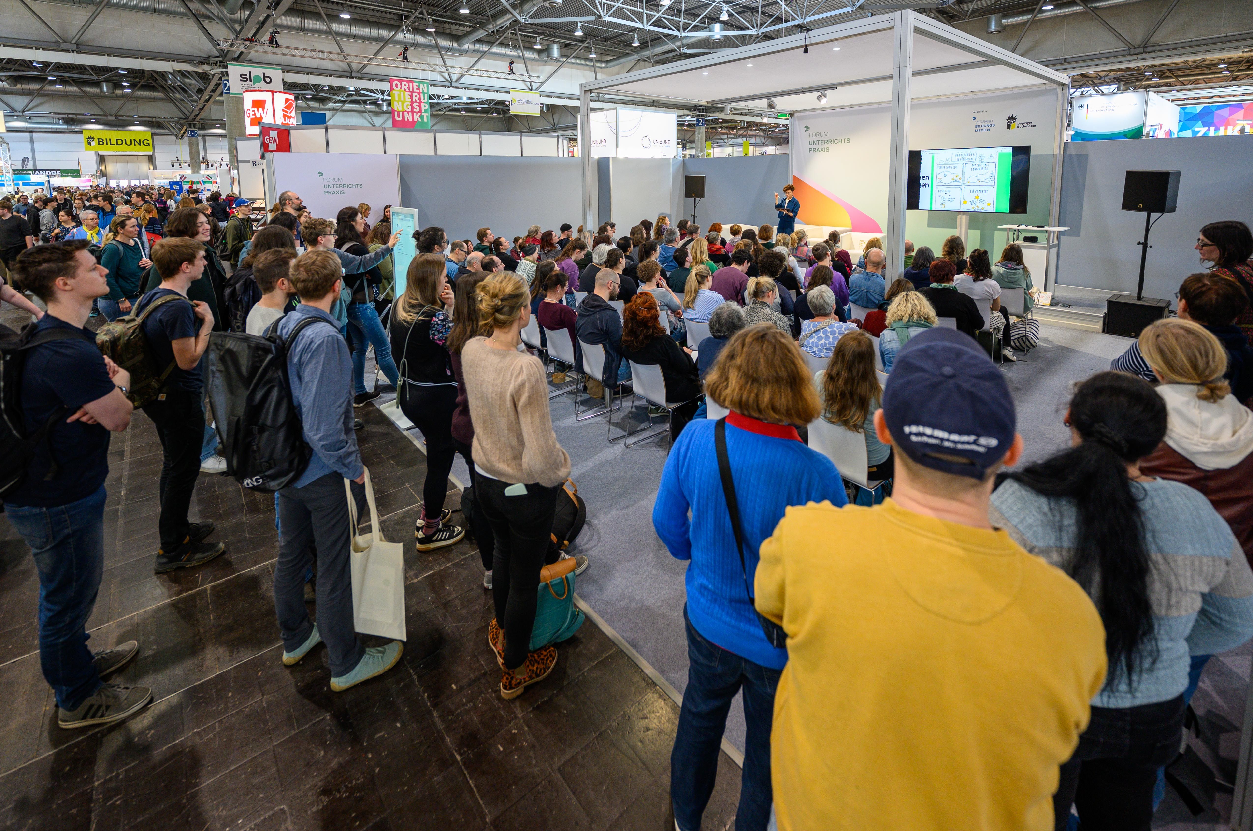 Messebesucher/-innen stehen um das Forum Unterrichtspraxis herum